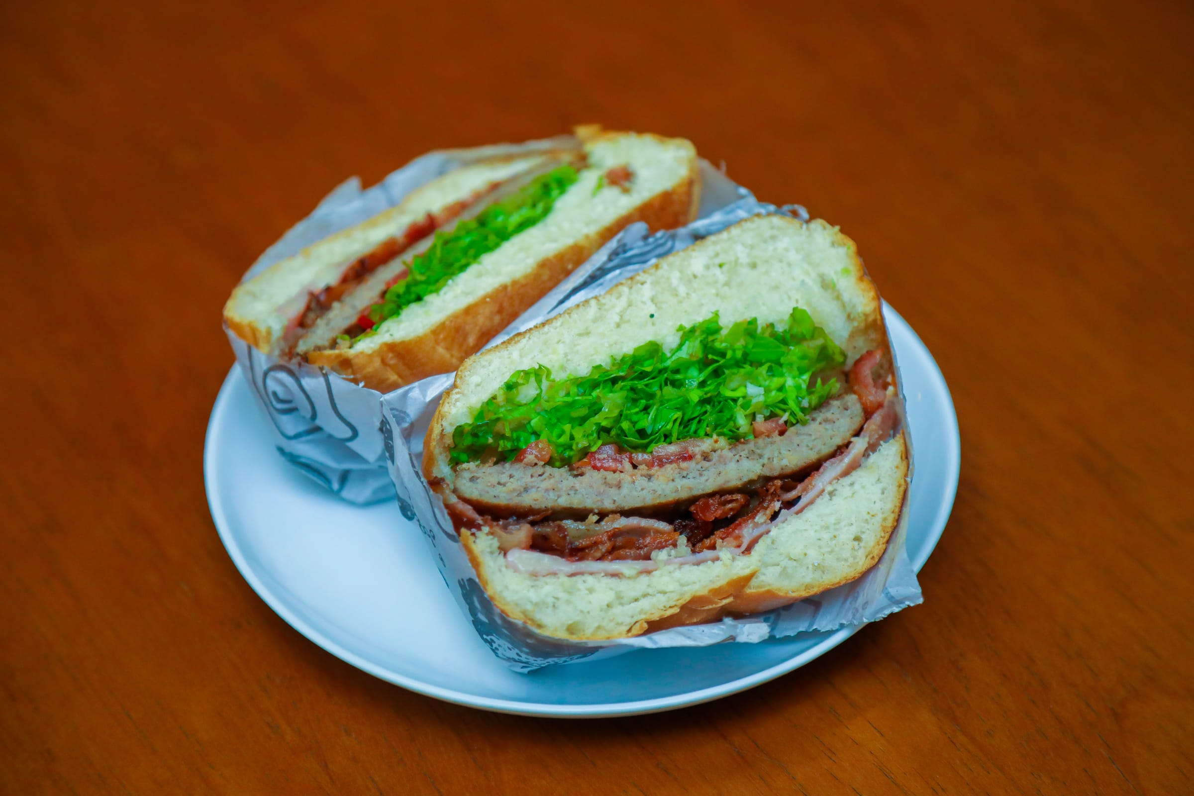 Lanche farto cortado ao meio servido no prato