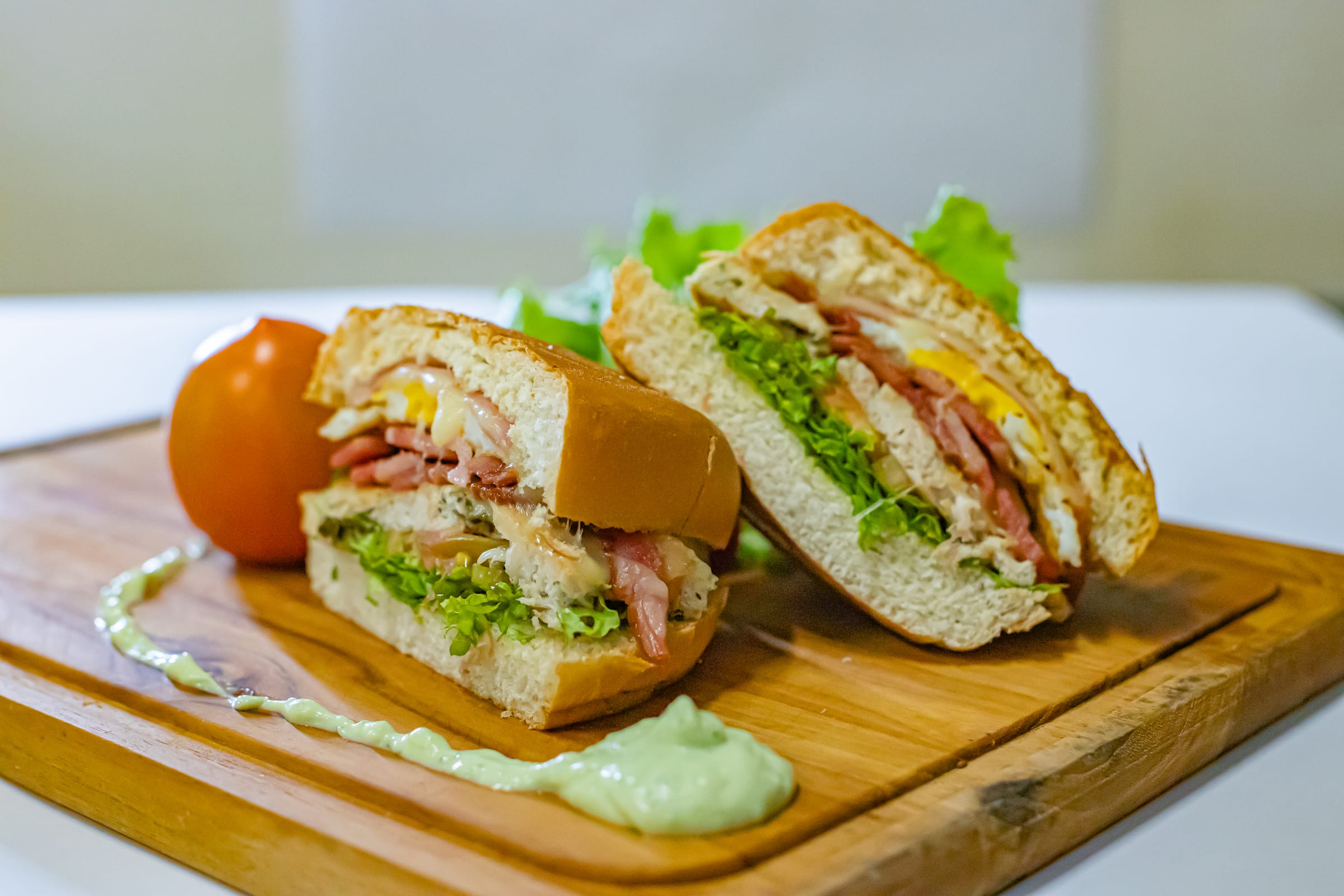 Lanche com bacon, ovo e salada servido na tábua de madeira