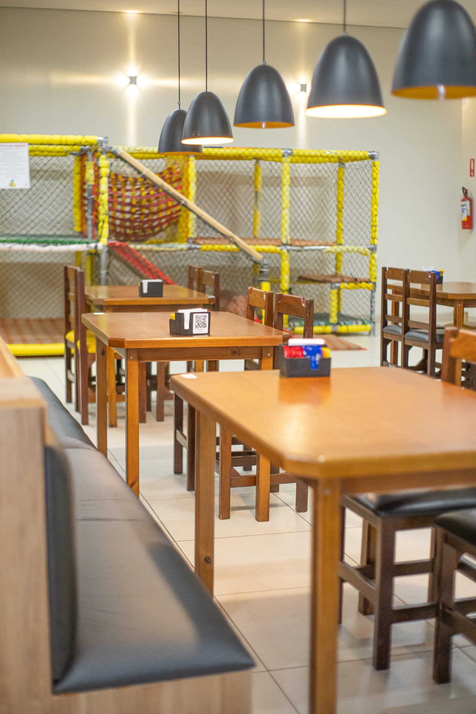 Mesas e bancos estofados com o playground ao fundo